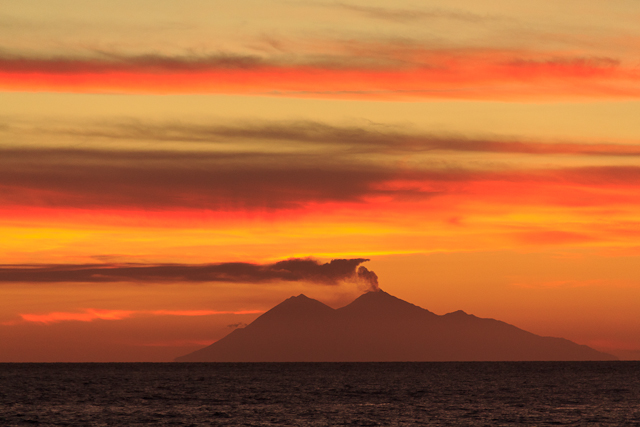 Atemberaubender Sonnenuntergang mit rauchendem Vulkan